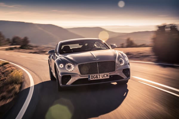 Обои Серебристый автомобиль Bentley Continental GT 2018 года на трассе